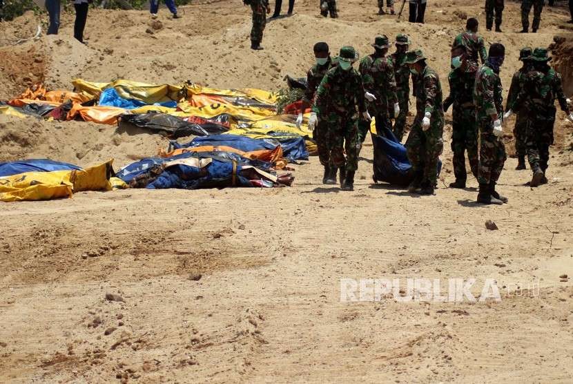 Prajurit TNI mengangkat jenazah korban gempa Palu di TPU Poboya Indah, Palu, Sulawesi Tengah, Selasa (2/10). 