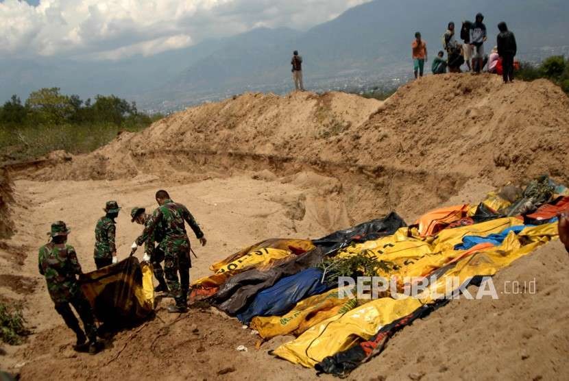 Prajurit TNI mengangkat jenazah korban gempa Palu di TPU Poboya Indah, Palu, Sulawesi Tengah, Selasa (2/10). 