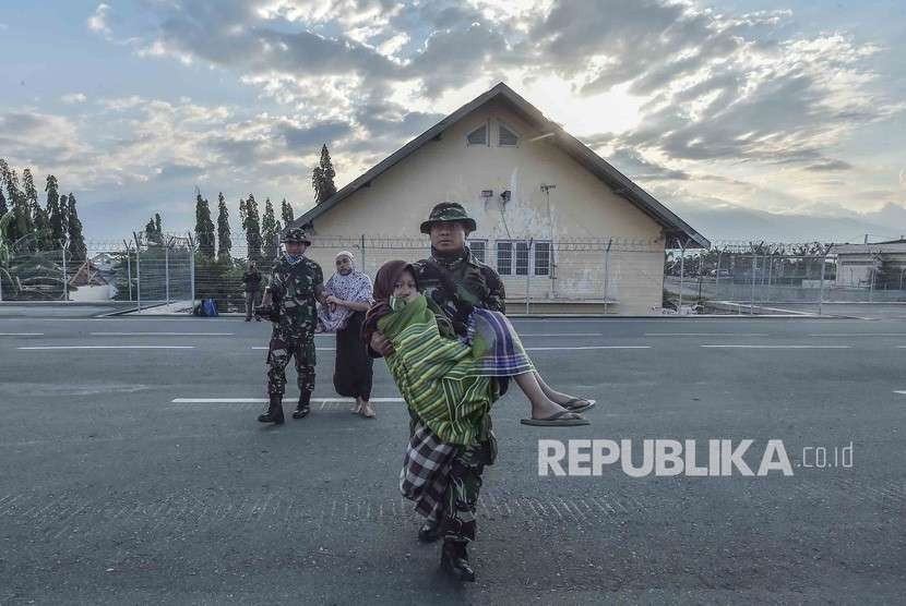 Prajurit TNI mengendong Korban gempa selamat di Bandara Mutiara Sis Aljufri untuk di evakuasi di Palu, Sulawesi Tengah, Sabtu (29/9). 