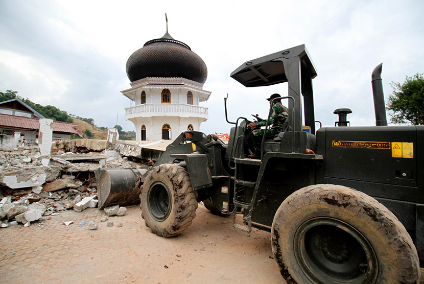 Prajurit TNI mengoperasikan alat berat untuk membersihkan puing Masjid Jamik Quba yang roboh akibat gempa bumi 6,5 SR di Pidie Jaya, Aceh, Sabtu (10/12).