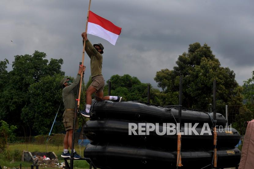 Prajurit Yon Taifib 2 Marinir TNI AL mengibarkan bendera merah putih setengah tiang di posko mereka di Pelabuhan Tanjung Wangi, Banyuwangi, Jawa Timur, Senin (25/4/2021). TNI AL mengibarkan bendera setengah tiang untuk menghormati 53 awak kapal selam KRI Nanggala-402 yang gugur di perairan Bali dan bendera setengah tiang tersebut akan dikibarkan selama 7 hari. 