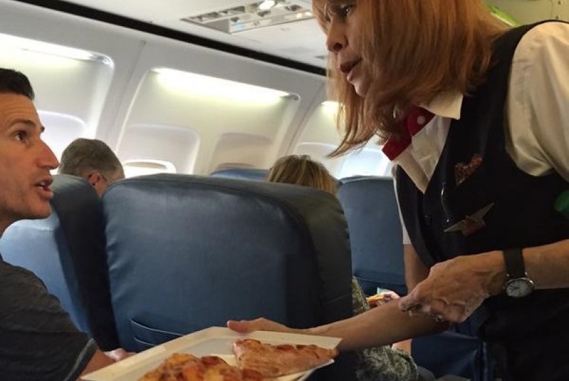 Pramugari Delta Airlines memberikan pizza kepada penumpang