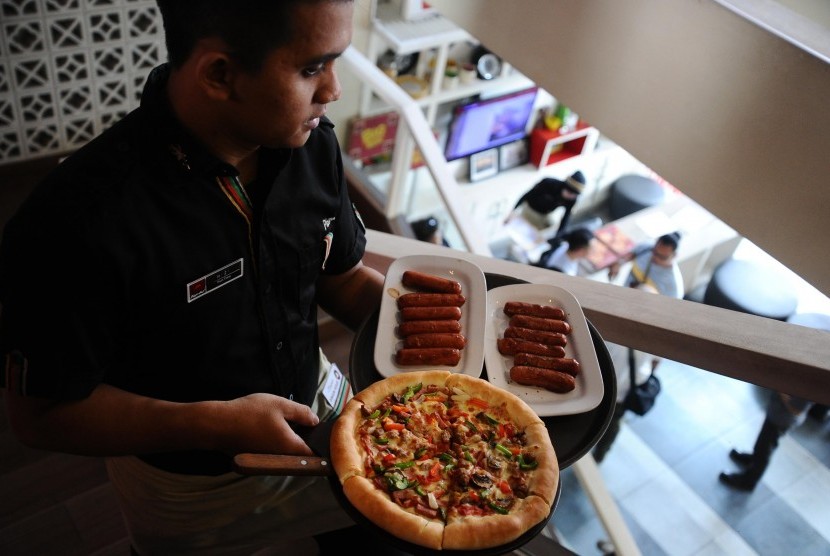 Pramusaji membawa loyang pizza saat melayani pengunjung di Pizza Hut, Jakarta.