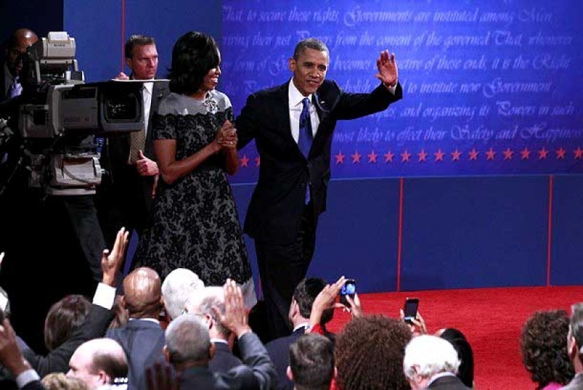  Presiden AS Barack Obama melambaikan tangan didampingi Michelle Obama saat meninggalkan panggung debat final  presiden AS di Boca Raton, Florida, Selasa (23/10). (Jason Reed/Reuters)