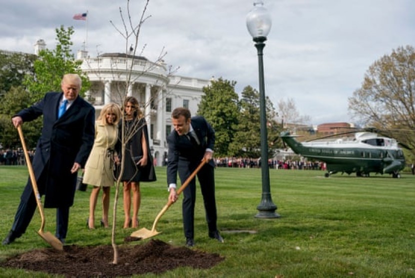 Presiden AS Donald Trump dan Presiden Prancis Emmanuel Macron menanam pohon ek simbol persahabatan di sisi selatan Gedung Putih pada April 2018. Keduanya ditemani ibu negara masing-masing.