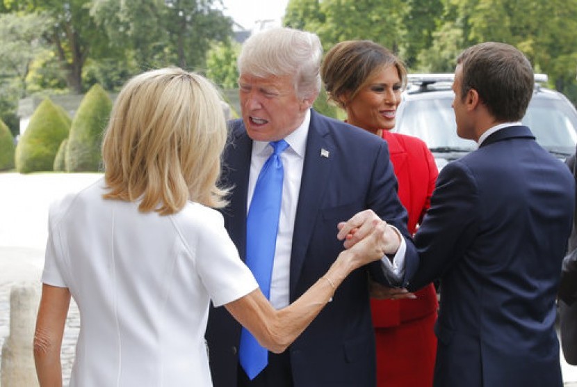 Presiden AS Donald Trump (kedua kiri) menyapa hangat Ibu Negara Prancis Brigitte (kiri). Tampak Presiden Prancis Emmanuel Macron menyambut Melania Trump di Paris, 13 Juli 2017.