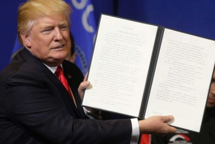 Presiden AS Donald Trump memegang kertas inpres sebelum menandatanganinya.  