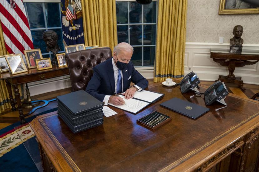 Presiden AS ke-46 Joe Biden di Oval Office. Di meja kerja tersebut, presiden terdahulu, Donald Trump, memasang tombol merah yang rupanya berfungsi untuk meminta diantarkan Diet Coke, minuman favoritnya.