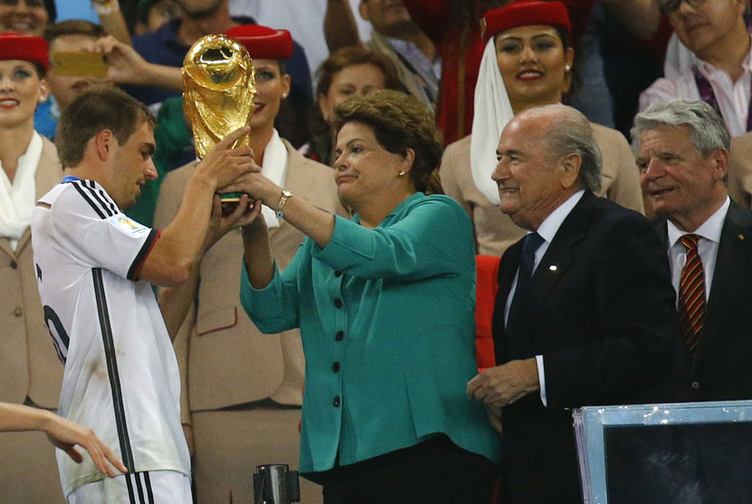 Presiden Brasil, Dilma Rousseff (dua kiri), menyerahkan trofi Piala Dunia kepada kapten Timnas Jerman, Philipp Lahm, usai memenangkan partai final mengalahkan Argentina 1-0 di Stadion Maracana, Rio de Janeiro, Ahad (13/7). 