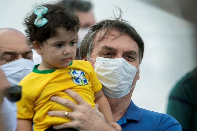 Presiden Brasil Jair Bolsonaro kembali mengabaikan protokol kesehatan Covid-19 dengan berbaur dengan para demonstran dan menggendong anak-anak.