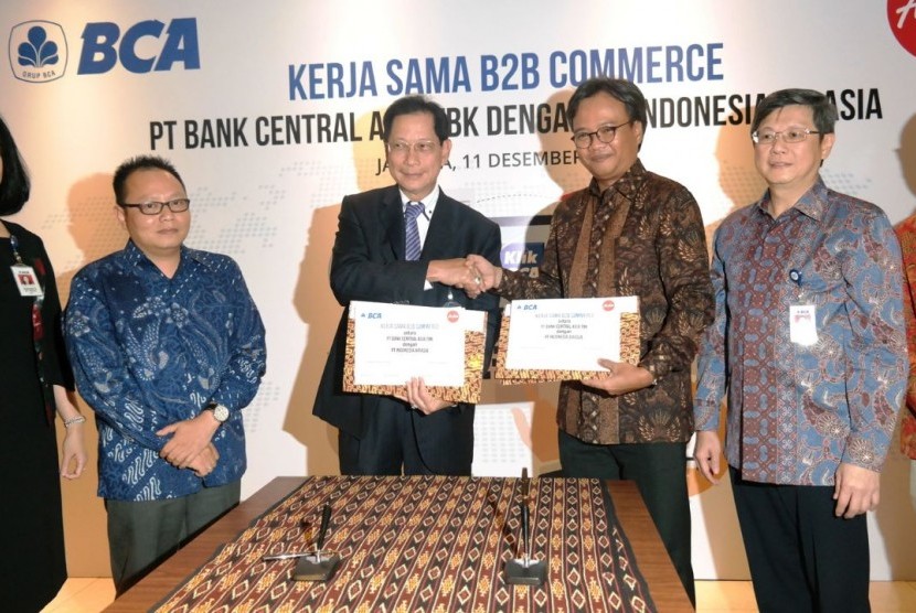 Presiden Direktur BCA Jahja Setiaatmadja (tengah kiri) berjabat tangan dengan CEO Grup AirAsia di Indonesia Dendy Kurniawan (tengah kanan), didampingi (kiri-kanan) Senior Vice President Cash Management BCA Rusdianti Salim, Direktur Niaga AirAsia Indonesia Rifai Taberi, Direktur BCA Henry Koenaifi, dan Head of Corporate Secretary AirAsia Indonesia Baskoro Adiwiyono, usai menandatangani perjanjian Kerja Sama Business to Business(B2B) Commerce antara BCA dan AirAsia Indonesia di Jakarta, Senin (11/12).