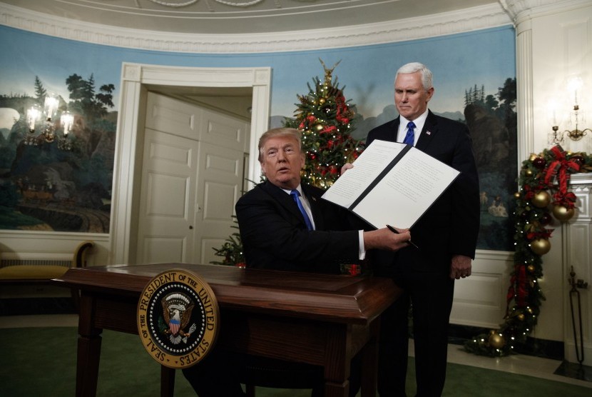 Presiden Donald Trump, didampingi oleh Wakil Presiden Mike Pence, memegang sebuah dokumen proklamasi yang ditandatanganinya untuk mengakui Yerusalem sebagai Ibu Kota Israel di Ruang Penerimaan Diplomatik Gedung Putih, Rabu (6/12), di Washington.
