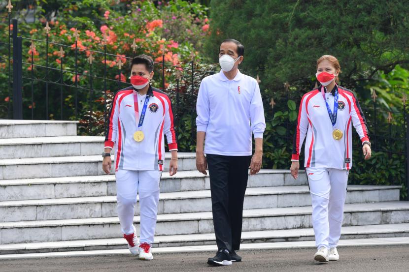 Presiden RI Joko Widodo berjalan bersama dengan atlet peraih medali emas Olimpiade Tokyo 2020 Greysia Polii (kanan) dan Apriyani Rahayu (kriri) saat menerima tim Indonesia pada Olimpiade Tokyo 2020, di Istana Bogor, Jawa Barat, Jumat (13/8).