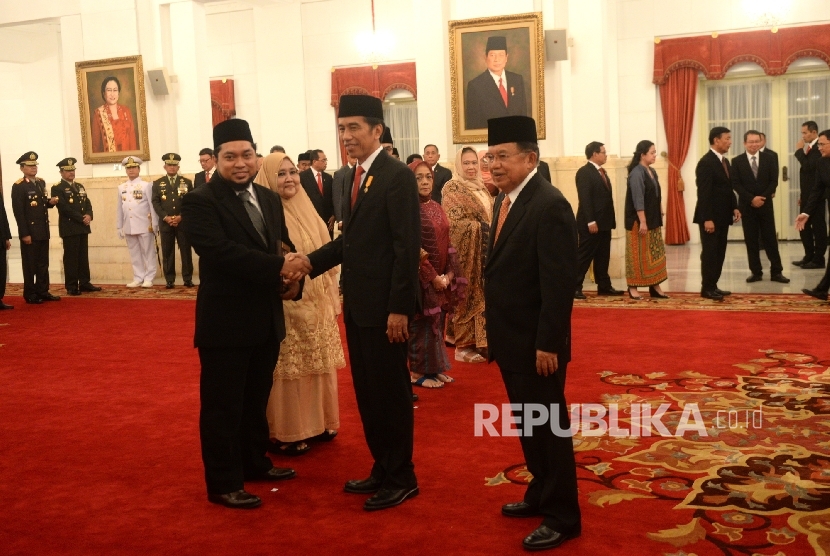 Presiden Joko Widodo bersama Wakil Presiden Jusuf Kalla memberikan selamat kepada Perwakilan dari keluarga Kyai Haji Raden Asad Syamsul Arifinusai penganugerahan Pahlawan Nasional di Istana Negara, Jakarta, Rabu (9/11).