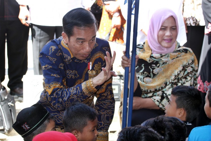 Presiden Joko Widodo dan Ibu Negara Iriana menghibur dan membagi buku bacaan kepada anak korban gempa di tenda pengungsian Ringblang Meurdu, Pidie Jaya, Provinsi Aceh, Kamis (15/12). 
