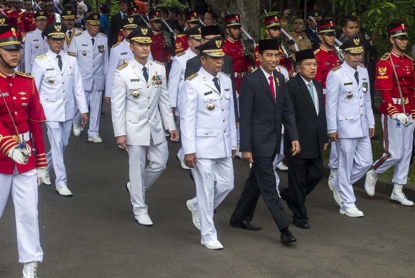 Presiden Joko Widodo dan Wapres Jusuf Kalla dan (tengah) beserta tujuh pasang Gubernur dan Wakil Gubernur terpilih dengan dikawal pasukan kehormatan berjalan bersama menuju Istana Negara untuk mengikuti acara pelantikan di Jakarta, Jumat (12/2).  