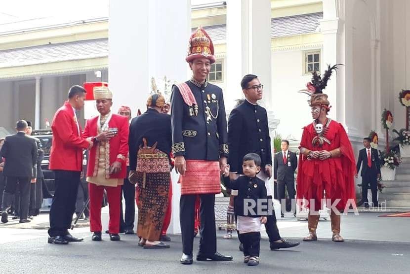 Presiden Joko Widodo (Jokowi) mengenakan pakaian adat asal Aceh untuk memperingati detik-detik proklamasi Kemerdekaan RI di Istana Merdeka, Jakarta, Jumat (17/8). Ia tampak bersama putranya Gibran Rakabuming dan cucunya Jan Ethes Srinarendra. 