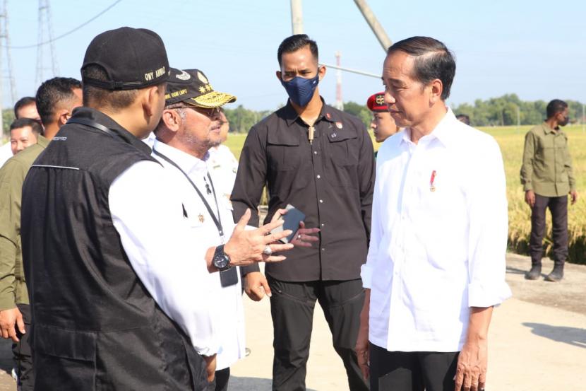 Presiden Joko Widodo (kanan) berbincang dengan Menteri Pertanian Syahrul Yasin Limpo (kiri)  di areal persawaan saat meninjau panen raya padi dalam kunjungan kerjanya di Ngawi, Jawa Timur, Sabtu (11/3/2023). 