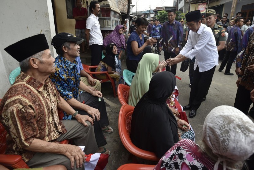 Presiden Joko Widodo (kanan) berjabat tangan dengan lansia saat membagikan paket sembako kepada warga. ilustrasi