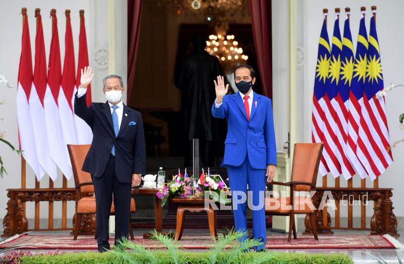 Presiden Joko Widodo (kanan) bersama Perdana Menteri Malaysia Muhyiddin Yassin (kiri) melambaikan tangan di veranda Istana Merdeka, Jakarta, Jumat (5/2/2021). Presiden Joko Widodo menerima kunjungan kenegaraan perdana dari PM Malaysia Muhyiddin Yassin dan kedua pemimpin negara tersebut membahas hubungan bilateral meliputi perlindungan WNI di Malaysia dan sejumlah isu kawasan dan global. 