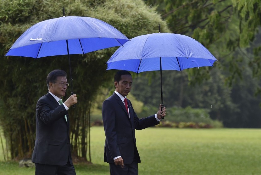 Presiden Joko Widodo (kanan) bersama Presiden Korea Selatan (Korsel) Moon Jae-in (kiri) bersiap menuju lokasi penanaman pohon di halaman belakang Istana Kepresidenan Bogor, Jawa Barat, Kamis (9/11). 