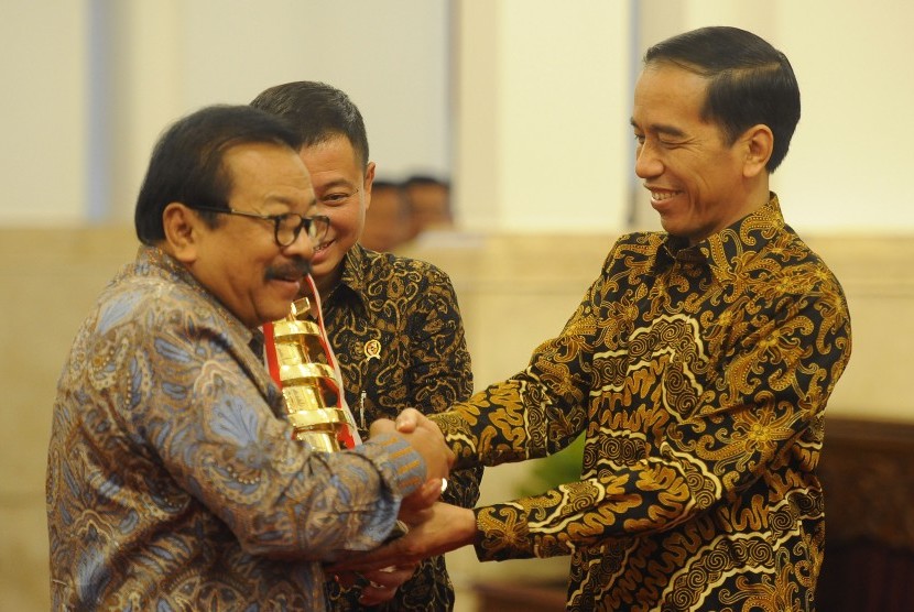 Presiden Joko Widodo (kanan) didampingi Menhub Ignasius Jonan (tengah) menyerahkan penghargaan Wahana Tata Nugraha Wiratama Kencana 2015 kepada Gubernur Jawa Timur Soekarwo (kiri) di Istana Negara, Jakarta, Rabu (23/12).  (Antara/Puspa Perwitasari)