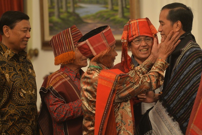 Presiden Joko Widodo (kanan) disaksikan Menko Polhukam Wiranto (kiri) menerima sematan Kain Ulos khas Batak dari perwakilan Masyarakat Hukum Adat (MHA) Pandumaan Sipituhuta Kabupaten Humbang Hasundutan, Sumut usai acara Pencanangan Pengakuan Hutan Adat Tah