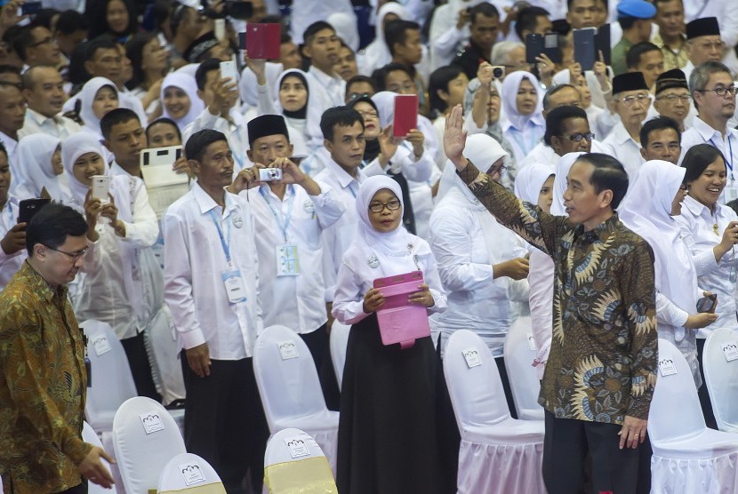 Presiden Joko Widodo (kanan) melambaikan tangan ke arah para guru yang hadir pada acara puncak Peringatan Hari Guru Nasional ke-21 Tahun 2015 di Istora Senayan, Jakarta, Selasa (24/11).