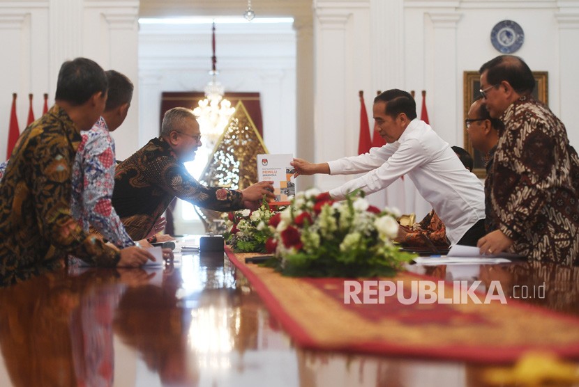 Presiden Joko Widodo (kanan) menerima buku laporan penyelenggaraan Pemilu Serentak tahun 2019 dari Ketua Komisi Pemilihan Umum (KPU) Arief Budiman dalam pertemuan di Istana Merdeka, Jakarta, Senin (11/11/2019).