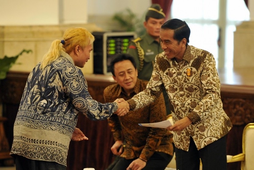 Presiden Joko Widodo (kanan) menerima dokumen tentang industri musik yang diserahkan musisi Andi Ayunir (kiri) disaksikan Kepala Badan Ekonomi Kreatif Triawan Munaf (tengah) saat menerima pengurus Asosiasi Industri Rekaman Indonesia (Asiri) dan Persatuan A