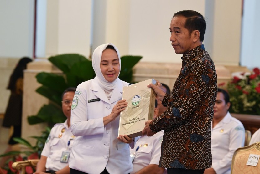 Presiden Joko Widodo (kanan) menerima katalog gempa bumi dan tsunami dari Kepala Badan Meteorologi, Klimatologi dan Geofisika (BMKG) Dwikorita Karnawati (kiri) saat membuka Rapat Koordinasi Nasional (Rakornas) BMKG tahun 2019 di Istana Negara, Jakarta, Selasa (23/7/2019). 