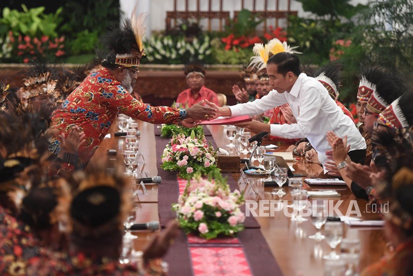 Presiden Joko Widodo (kanan) menerima map berisi saran dari perwakilan tokoh Papua Abisai Rollo (kiri) dalam pertemuan di Istana Negara, Jakarta, Selasa (10/9/2019).