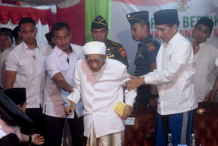 Presiden Joko Widodo (kanan) menuntun Pimpinan Pondok Pesantren Al-Anwar Sarang Maimoen Zubair (tengah) saat menghadiri acara Sarang Berzikir Untuk Indonesia Maju di Rembang, Jawa Tengah, Jumat (1/2/2019).