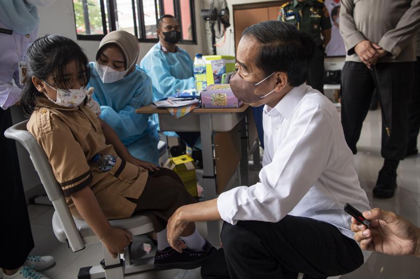 Presiden Joko Widodo (kanan) menyaksikan seorang anak yang akan menjalani vaksinasi Covid-19 di Kompleks SDN Cideng, Gambir, Jakarta Pusat, Rabu (15/12/2021). Presiden meninjau langsung vaksinasi COVID-19 bagi anak-anak usia 6-11 tahun.