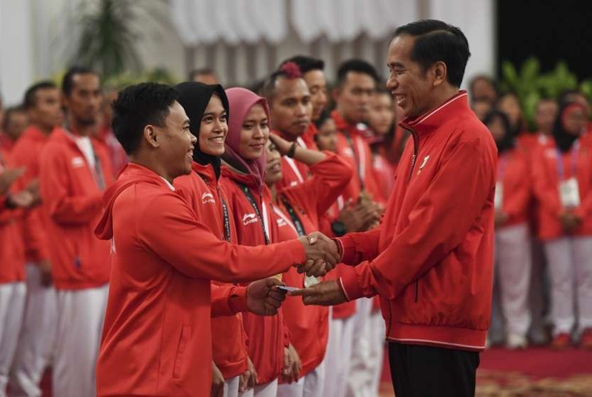 Presiden Joko Widodo (kanan) menyalami dan memberikan buku tabungan kepada lifter Eko Yuli Irawan (kiri) saat pemberian bonus kepada atlet peraih medali di Istana Negara, Jakarta, Minggu (2/9). Pemerintah memberikan bonus kepada para atlet yang berhasil meraih medali dalam ajang Asian Games 2018.