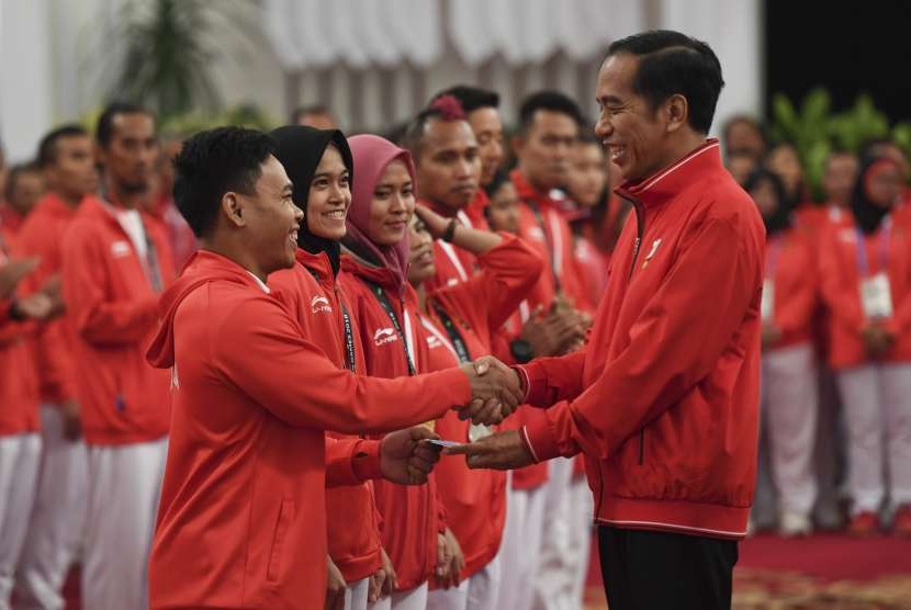 Presiden Joko Widodo (kanan) menyalami dan memberikan buku tabungan kepada lifter Eko Yuli Irawan (kiri) saat pemberian bonus kepada atlet peraih medali di Istana Negara, Jakarta, Ahad (2/9). 