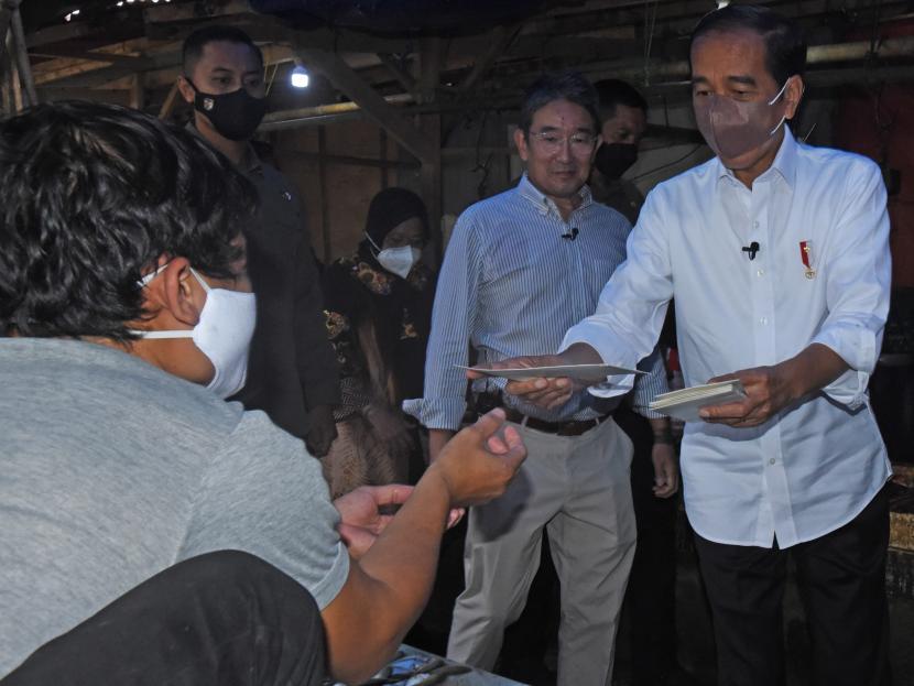Presiden Joko Widodo (kanan) menyerahkan bantuan langsung tunai (BLT) kepada warga saat mengunjungi pasar tradisional. (Ilustrasi)