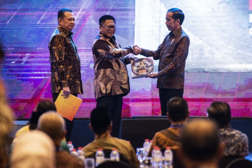 Presiden Joko Widodo (kanan) menyerahkan buku kepada Ketua DPD Oesman Sapta Odang (tengah) disaksikan Ketua DPR Bambang Soesatyo (kiri) dalam Peluncuran Geoportal Kebijakan Satu Peta dan Buku Kemajuan Infrastruktur Nasional Tahun 2018, di Jakarta, Selasa (11/12/2018). 