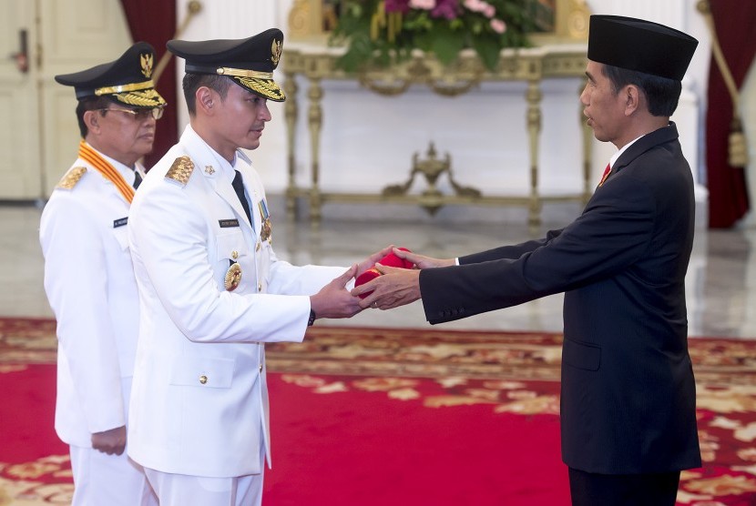 Presiden Joko Widodo (kanan) menyerahkan petikan Keppres kepada pasangan Gubernur dan Wakil Gubernur terpilih Jambi, Zumi Zola Zulkifli (tengah) dan Fachrori Umar (kiri) di Istana Merdeka, Jakarta, Jumat (12/2).