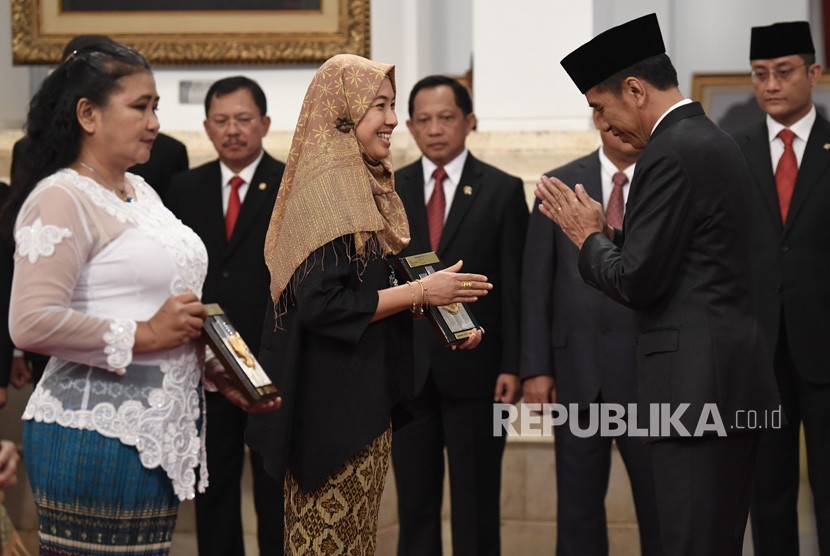 Presiden Joko Widodo (kanan) menyerahkan plakat anugerah gelar pahlawan nasional kepada ahli waris KH Masjkur di Istana Negara, Jakarta, Jumat (8/11/2019).