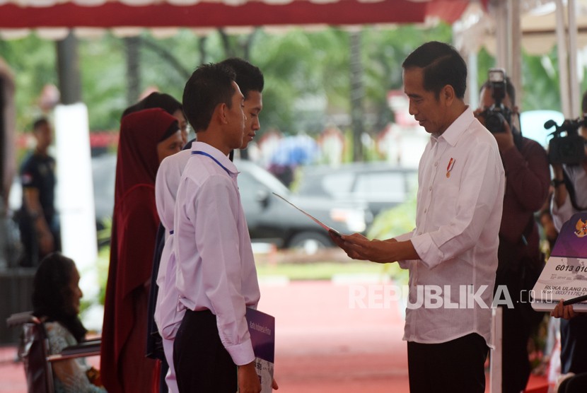 Presiden Joko Widodo (kanan) menyerahkan secara simbolik Kartu Program Keluarga Harapan (PKH) dan Kartu Indonesia Pintar (KIP) di Lapangan Syech Yusuf, Kabupaten Gowa, Sulawesi Selatan, Kamis (15/2).