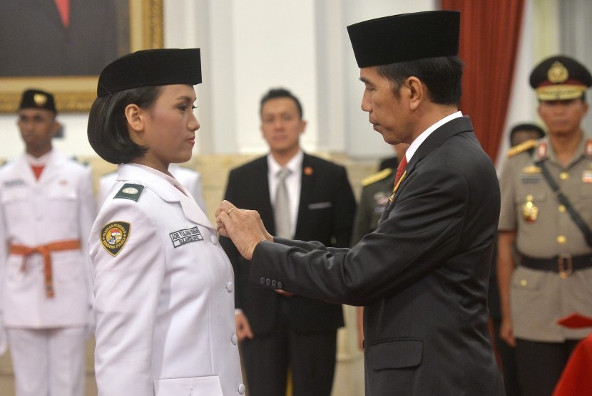 Presiden Joko Widodo (kanan) secara simbolis mengukuhkan Pasukan Pengibar Bendera Pusaka (Paskibraka) Nasional 2016 yang akan bertugas dalam upacara Peringatan Detik-Detik Proklamasi HUT ke-71 RI di Istana Negara, Jakarta, Senin (15/8).