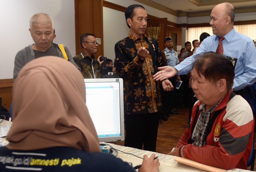 Presiden Joko Widodo (kedua kanan berdiri) berbincang dengan petugas pajak saat melayani wajib pajak yang ikut serta dalam program Pengampunan Pajak di Kantor Pelayanan Pajak Gabungan di Jalan M.I. Ridwan Rais, Jakarta, Rabu (28/9). 