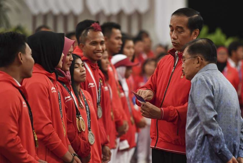 Presiden Joko Widodo (kedua kanan) bersama Wakil Presiden Jusuf Kalla melihat isi buku tabungan saat pemberian bonus kepada atlet peraih medali di Istana Negara, Jakarta, Minggu (2/9). 