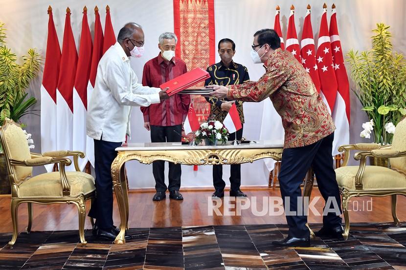 Presiden Joko Widodo (kedua kanan) dan Perdana Menteri Singapura Lee Hsien Loong (kedua kiri) menyaksikan Menkum Ham Yasonna Laoly (kanan) dan Mendagri Singapura K Shanmugam bertukar dokumen terkait perjanjian ekstradisi di The Sanchaya Resort Bintan, Kabupaten Bintan, Kepulauan Riau, Selasa (25/1/2022). 
