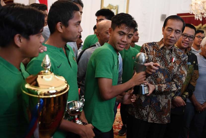 Presiden Joko WIdodo (kedua kanan) didampingi Menpora Imam Nahrawi (kanan) memegang piala bersama pemain Timnas U-16 di Istana Merdeka, Jakarta, Kamis (4/10). 