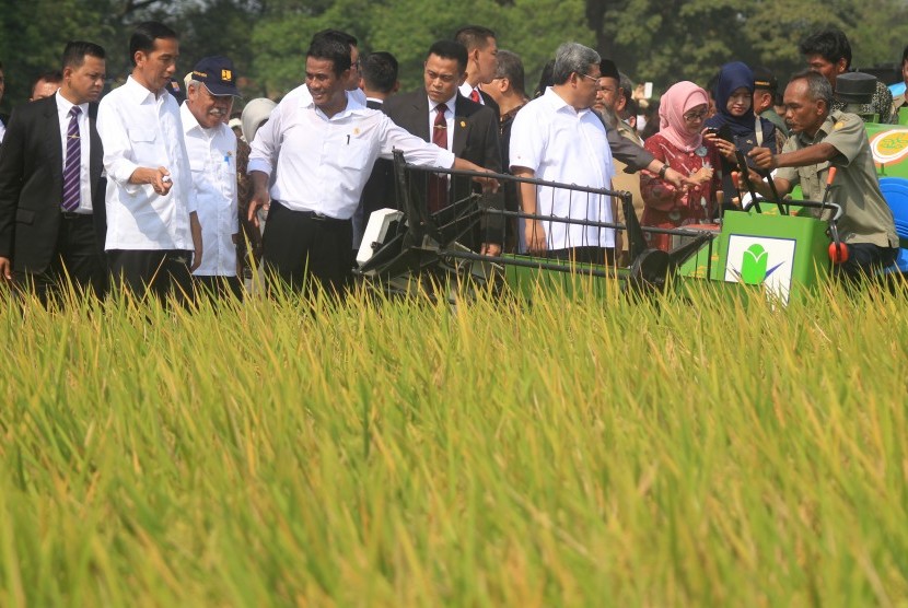 Presiden Joko Widodo (tengah) didampingi Gubernur Jawa Barat, Ahmad Heryawan (ketiga Kanan) bersama Menteri Pertanian, Andi Amran Sulaiman (kedua Kanan) dan Menteri PU - Pera, Basuki Hadimoeljono (kiri) melihat penanaman padi dengan mesin tanam (rice trans