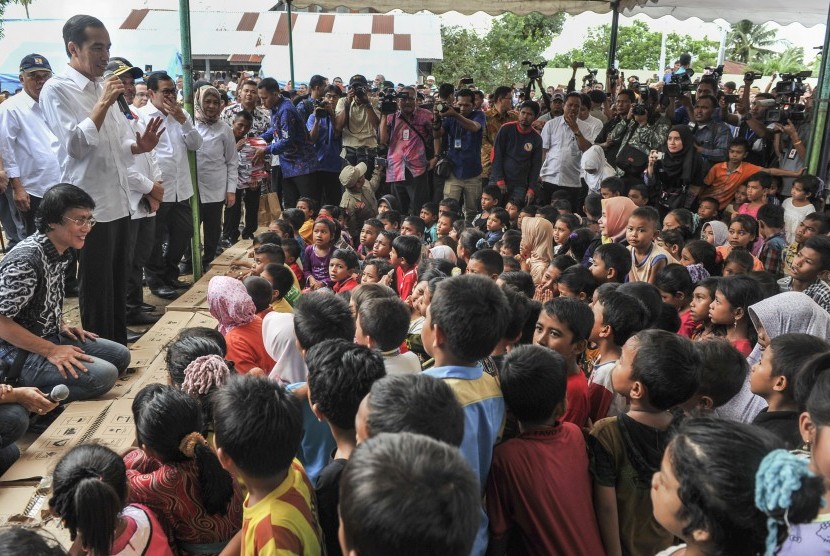 Presiden Joko Widodo (kedua kiri) didampingi Menteri Kesehatan Nila F. Moeloek (kelima kiri), Seskab Pramono Anung (keempat kiri) dan pemerhati anak Seto Mulyadi (kiri) menyapa anak-anak korban gempa di halaman Masjid Atta Darut, Pidie Jaya, Aceh, Jumat (9