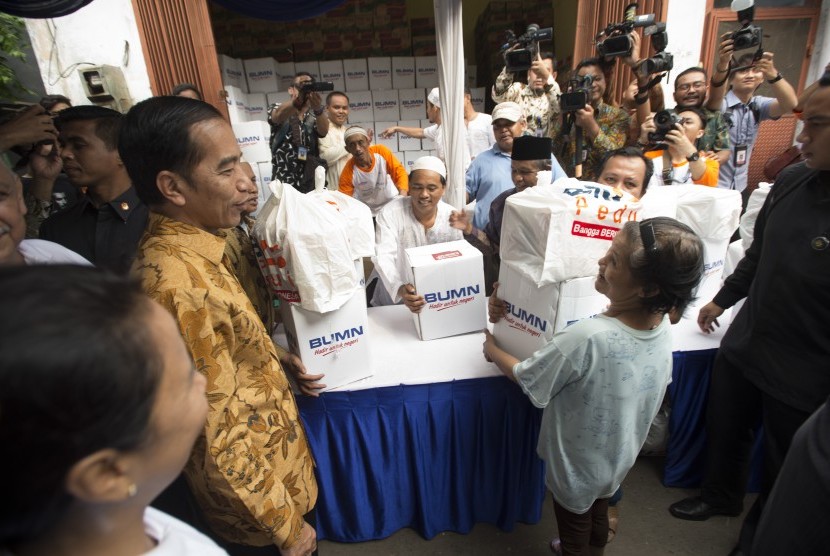 Presiden Joko Widodo (kedua kiri) menyaksikan pembagian sembako kepada warga di daerah Rawa Bebek, RW 11, RT 7, Jakarta, Selasa (13/6). 