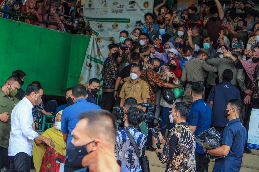 Presiden Joko Widodo (kedua kiri) menyapa warga saat mengunjungi Pasar Cibinong di Kabupaten Bogor, Jawa Barat, Selasa (17/5/2022). Dalam kunjungannya, Presiden menyerahkan bantuan modal usaha UMKM beserta Bantuan Langsung Tunai (BLT) minyak goreng. 